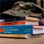 camouflage hat with brim atop a stack of books